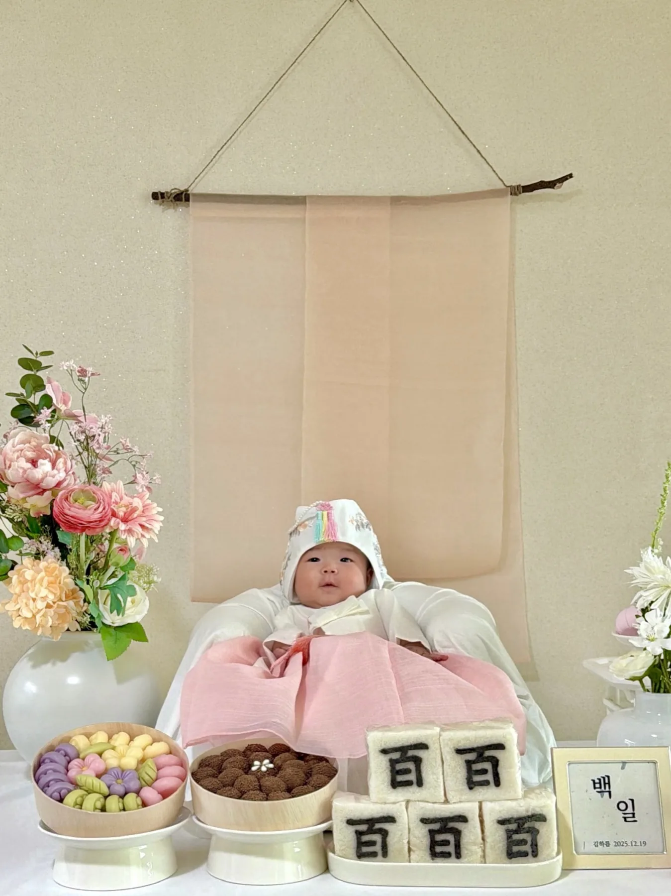 분홍 한복을 입고 백일상 앞에 누운 하름이